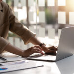 businesswoman sitting on a laptop computer with documents on the